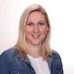 Frau Riesle trägt langes, blondes Haar und lächelt freundlich.