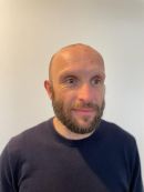 Herr Haas trägt einen Vollbart und lächelt freundlich