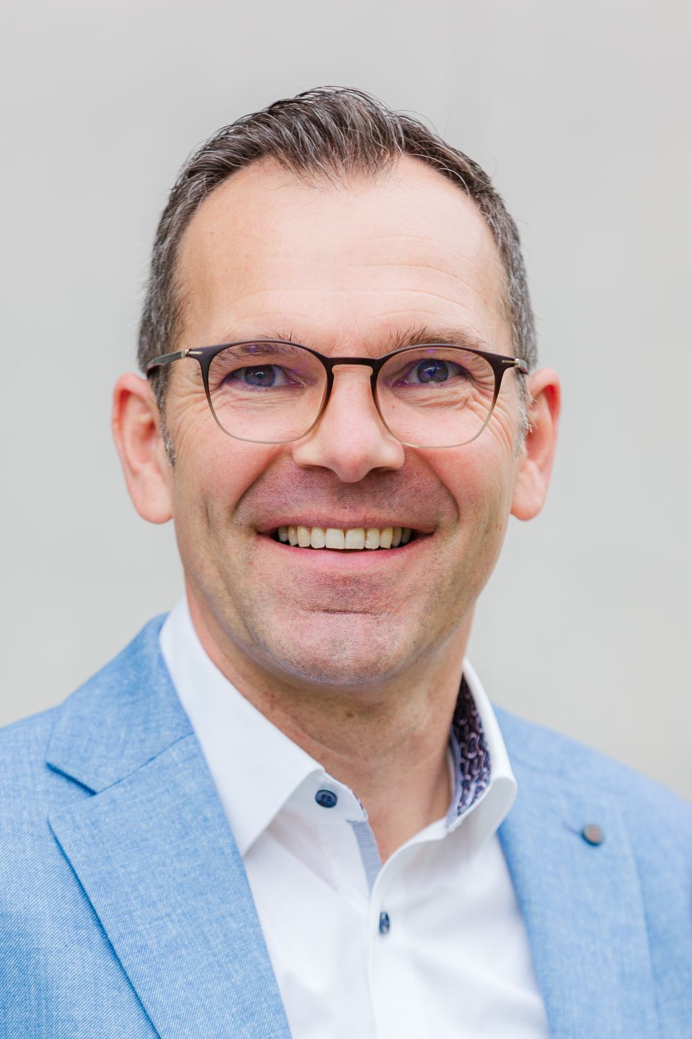 Das Bild zeigt Herrn Schneeman. Er trägt kurze, dunkle Haare und eine Brille. Er lächelt freundlich.