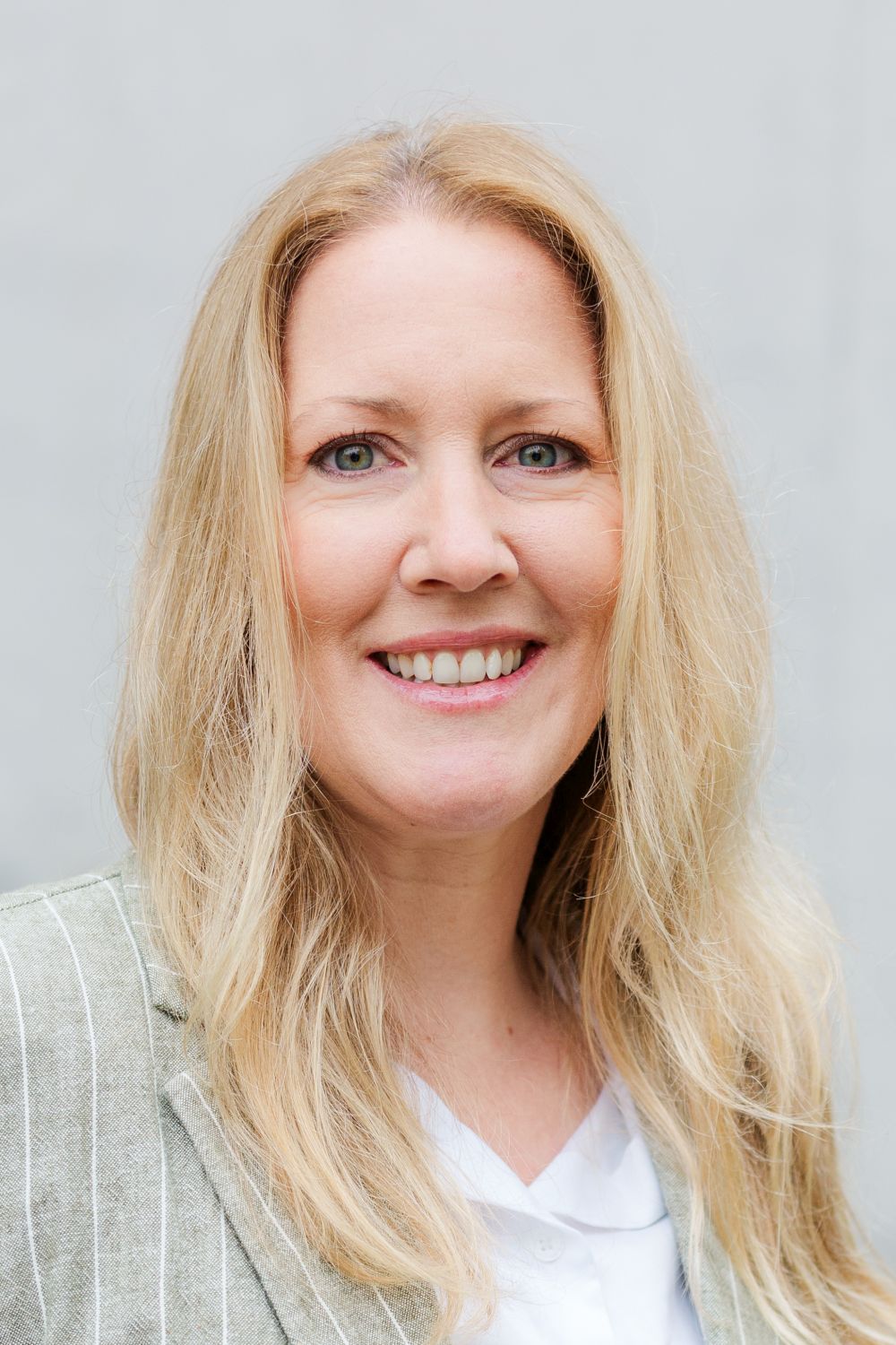 Frau Held trägt lange, blonde Haare und lächelt freundlich.