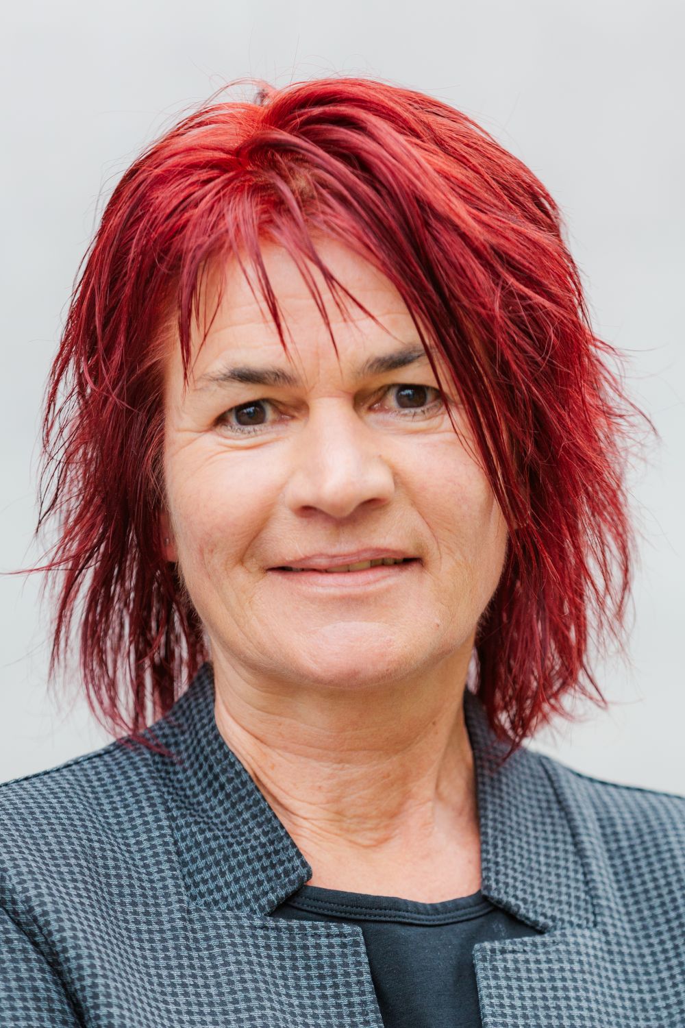 Das Bild zeigt Frau Spengler. Sie trägt kurze, rote Haare und lächelt freundlich.
