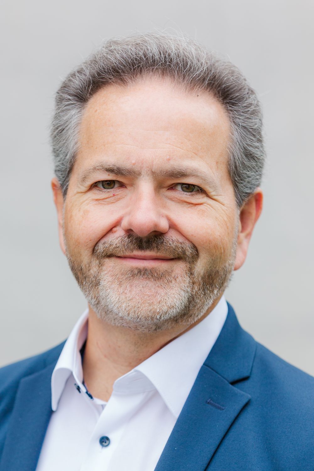 Das Bild zeigt Herrn Möllen. Er trägt kurze, graue Haare und einen Bart. Er lächelt freundlich.