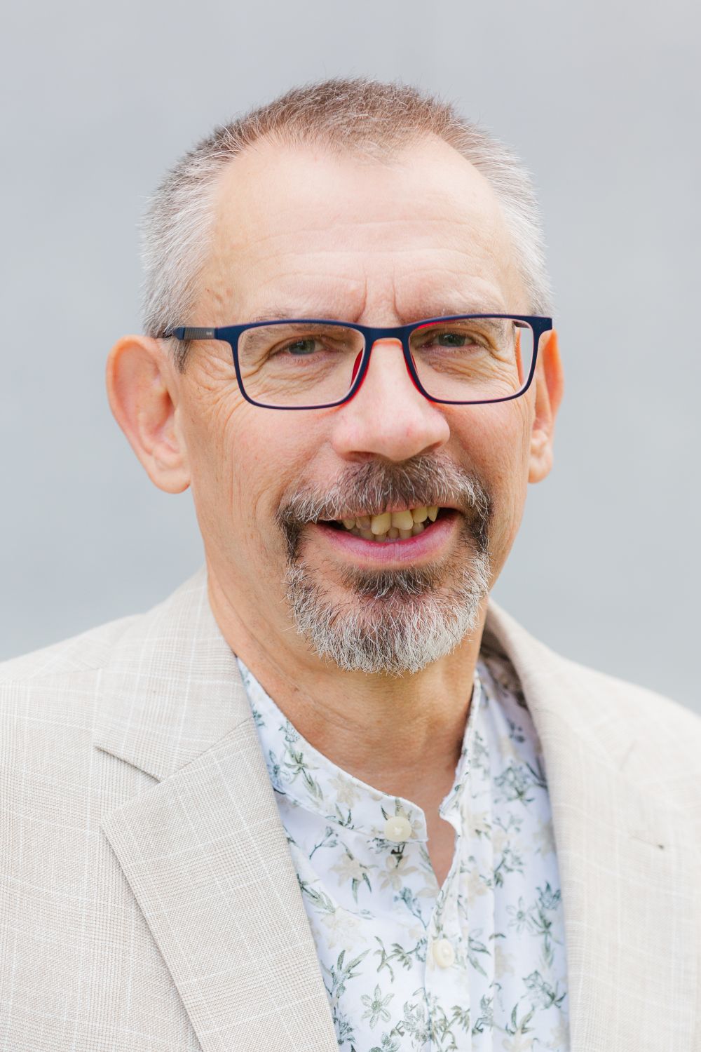 Das Bild zeigt Herrn Böhm. Es trägt kurze, graue Haare, eine Brille und einen Bart. Er lächelt freundlich.