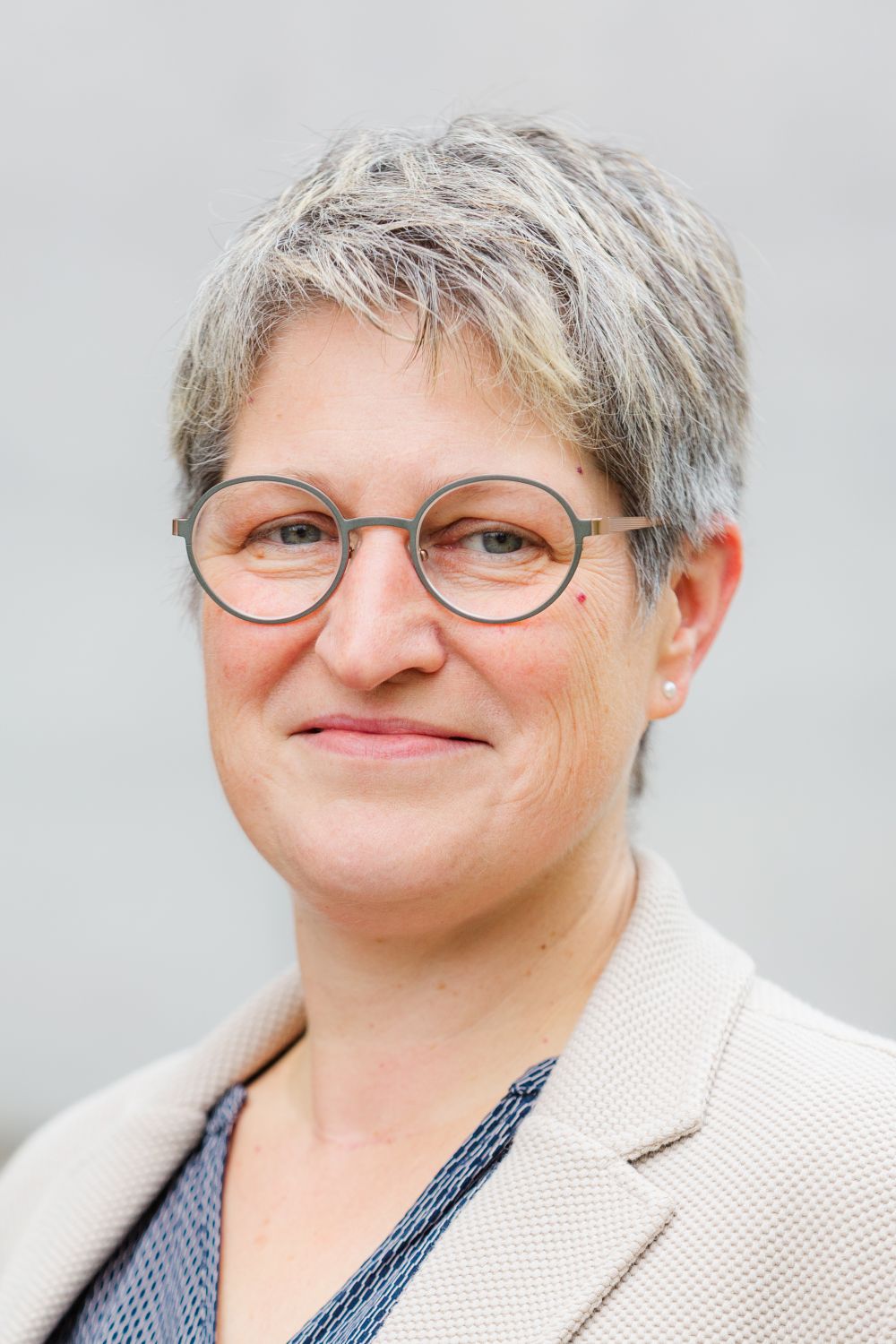 Das Bild zeigt Frau Neuwirth. Sie trägt kurze, blonde Haare und eine Brille. Sie lächelt freundlich.